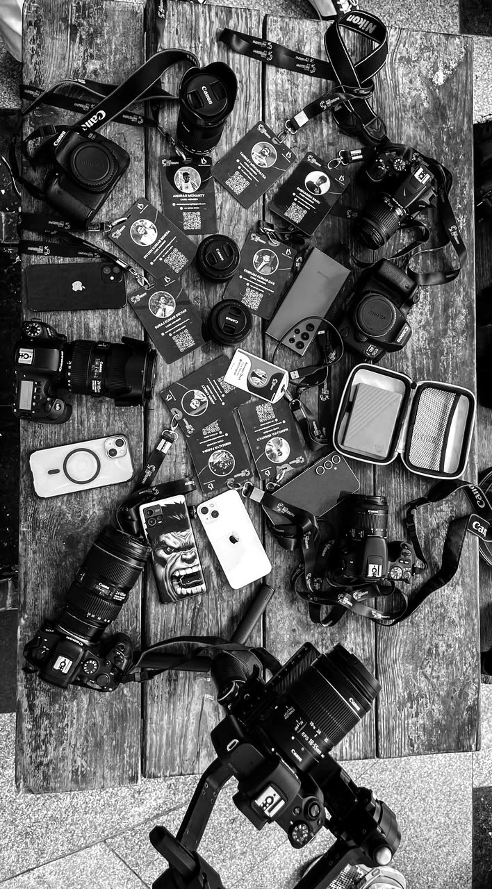 Camera equipment, lenses and ID cards laid out on a wooden table